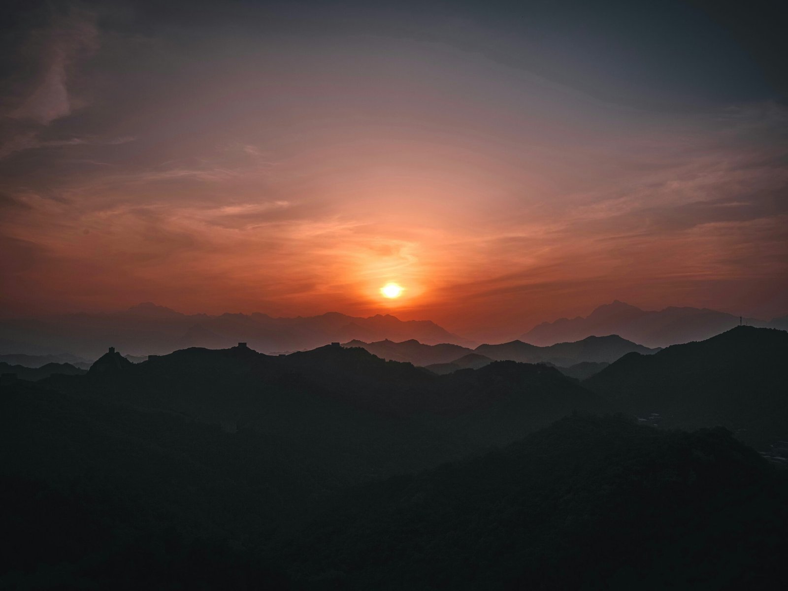 the sun is setting over a mountain range